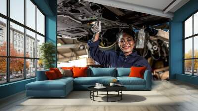 Smiling black mechanic woman working underneath car in auto repair, Car Mechanic Wall mural