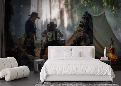 Three cowboys are relaxing playing and listening music in outdoor camping with the accommodation tent. Wall mural