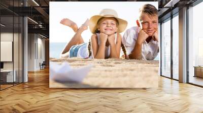  Boy and girl sitting together on sandy beach Wall mural