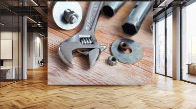 Adjustable wrench with bolts and melallic tools on wooden surface Wall mural