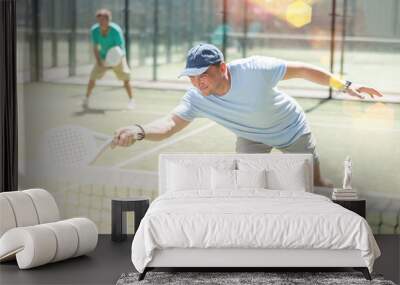 Adult men in doubles playing paddle tennis on tennis court Wall mural