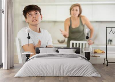 Adult woman during family quarrel with young guy in kitchen at home Wall mural