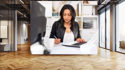 Busy female entrepreneur in office with papers and laptop Wall mural