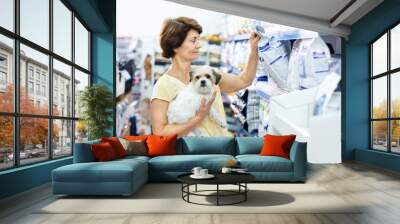 Careful senior woman visiting pet shop in search of dry food for her dog Wall mural