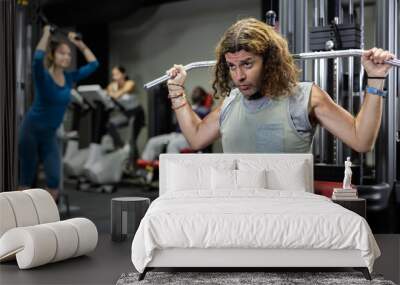 Caucasian man training on lat pull down machine in gym Wall mural