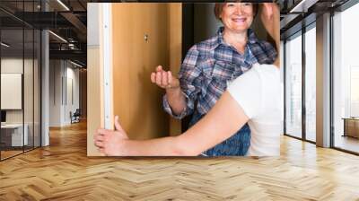 Cheerful greeting of two women at the door Wall mural