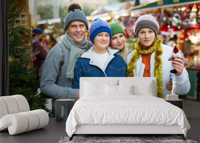 Cheerfull family with two teenagers posing with christmas gifts at Xmas market Wall mural