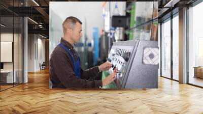 Confident glass factory worker at workplace with control panel, controlling technical process in workshop Wall mural