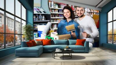 Couple purchasing tools for house improvements in paint supplies store Wall mural