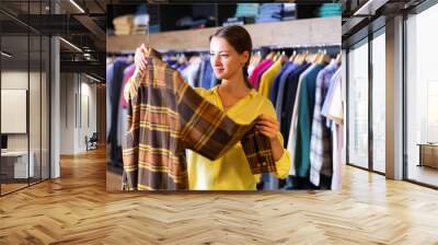 Cute woman buys checkered shirt in the fashion store. High quality photo Wall mural