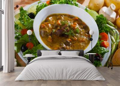 Delicious cooked goulash from chicken hearts served with vegetables and fresh lettuce at plate.. Wall mural