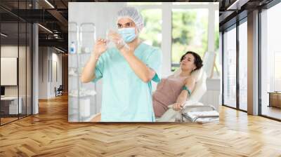 Doctor anesthetist checks the syringe before injection to the patient Wall mural