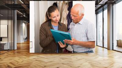 Elderly man filling  agreement papers with social worker at home Wall mural