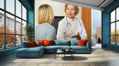 Elderly physician doing check up of sick female patient Wall mural