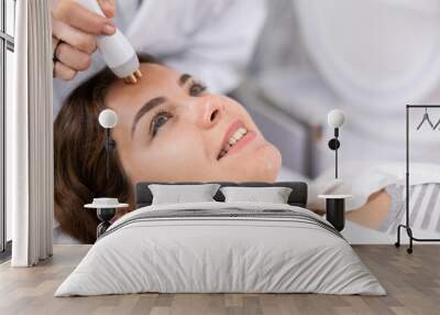 Face of relaxed young woman having radiolifting of her face by means of apparatus for aesthetic procedures Wall mural