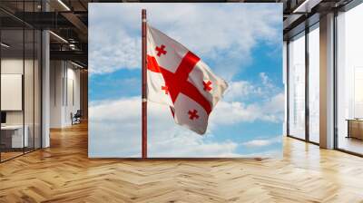 Georgian national flag flying on flagstaff in background of blue cloudy sky Wall mural