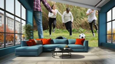 girl and three boys playing football in spring park and smiling Wall mural