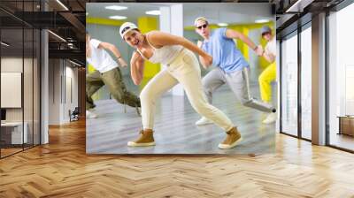 Group of cool, active teenage dancers having fun and learning new dance exercise movement in studio Wall mural