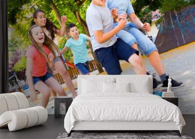 Happy children  playfully running after ball outdoors in park Wall mural