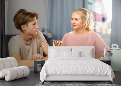 Happy family of mother and teenage son enjoying conversation, sitting at kitchen at home Wall mural