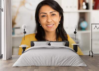 Happy smiling Latin American businesswoman standing in office and looking at camera Wall mural