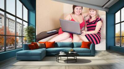 happy women sitting on sofa with laptop Wall mural