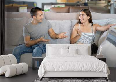 Happy young couple choosing a soft new sofa in a furniture store Wall mural