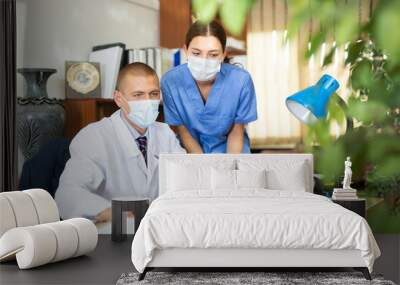 Head in protective mask gives task to assistant at office at table Wall mural