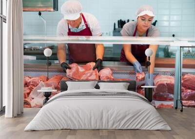 In local butcher shop, elderly male seller prepares order of pork ribs for regular customer. Seller assistant puts beef offal in window Wall mural