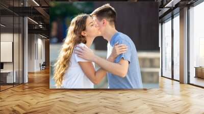 Kiss on cheek of boy and girl on the street of summer city Wall mural