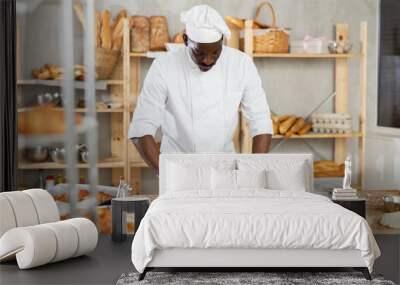 Making yeast dough in bakery - male baker rolling out dough with a rolling pin Wall mural