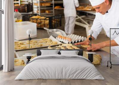 male baker in white uniform rolling out dough in kitchen Wall mural