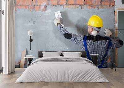 Male in the helmet is plastering the wall Wall mural