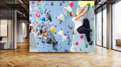 Man climbing a tall, indoor, man-made rock climbing wall Wall mural