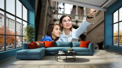 Mother and daughter consulting guide in phone Wall mural