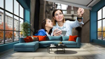 Mother and daughter consulting guide in phone Wall mural