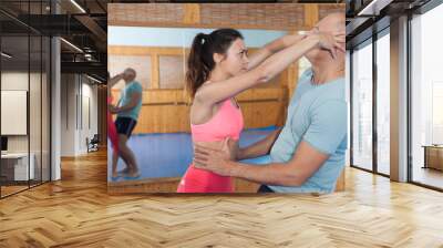 Ordinary female is fighting with trainer on the self-defense course for woman in sport club Wall mural