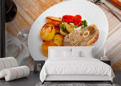 Portion of roasted lamb leg with potatoes and pepper served on plate. Wall mural