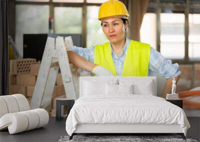 Portrait of a confident woman builder standing near a stepladder on a construction site indoors Wall mural