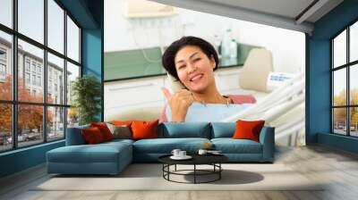 Portrait of a satisfied asian woman patient sitting in a dental chair in the clinic office Wall mural