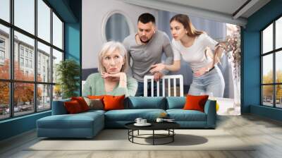 Portrait of annoyed stressed senior woman ignoring her adult children scolding her at home Wall mural