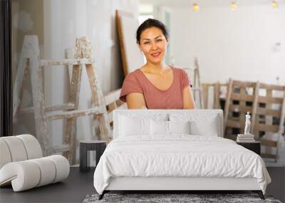 Portrait of asian woman worker standing at stepladder in apartment during repair works. Wall mural