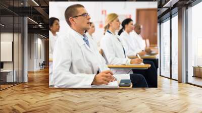 Portrait of confident man doctor listening to lecture within refresher course. Professional development concept Wall mural