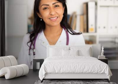 Portrait of confident smiling female doctor in white lab coat standing in modern medical office Wall mural