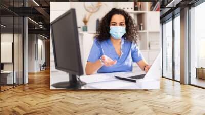 Portrait of confident woman doctor in face mask explaining prescription to patient in office in hospital Wall mural