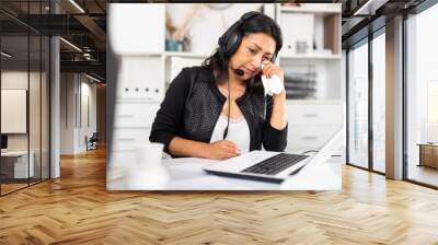 Portrait of disappointed crying female customer support phone operator with headphones during work in call center Wall mural