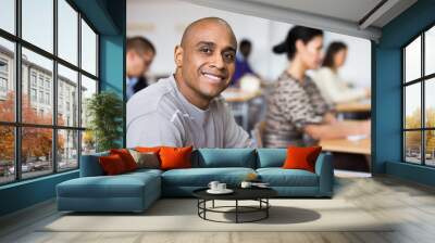 Portrait of focused young adult male studying in classroom with colleagues Wall mural