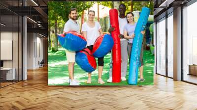 Portrait of happy friends with inflatable logs and pillows at an amusement park Wall mural