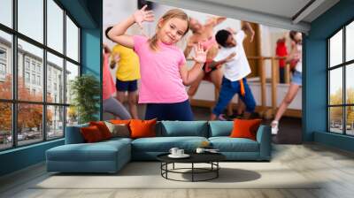 Portrait of little girl doing exercises during group class in dance center Wall mural