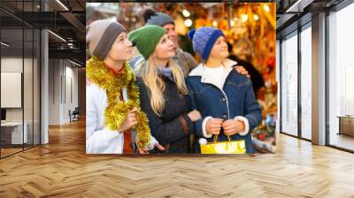 Portrait of positive family of four choosing christmas balls at Xmas street fair Wall mural